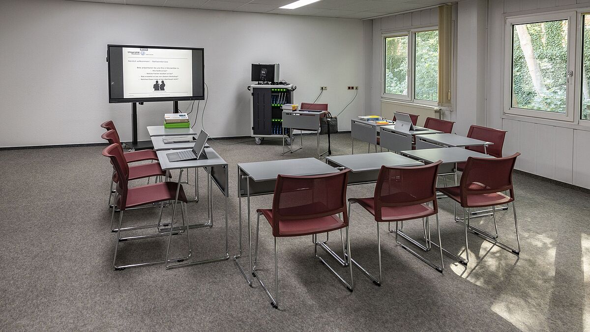 Ansicht Lehr-Lern-Raum der UB mit elektronischer Tafel, Tischen und Stühlen.