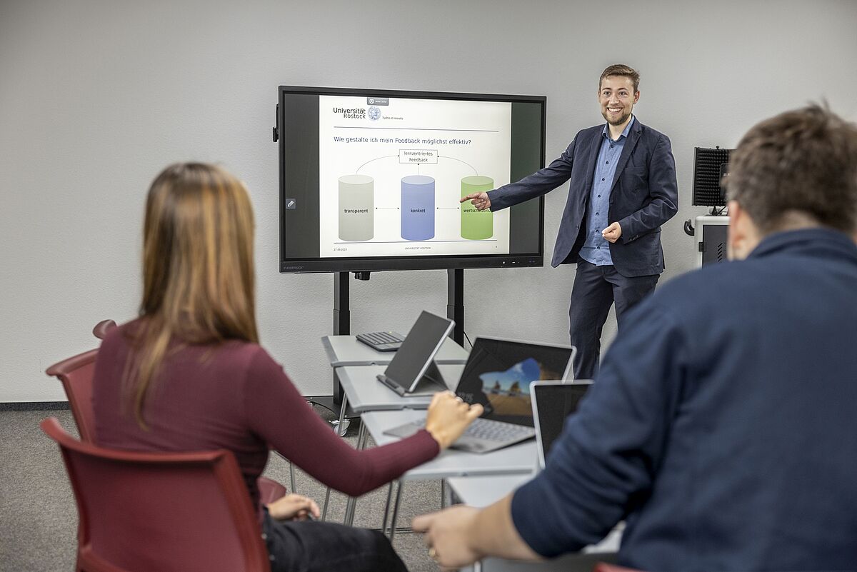 Ansicht Lehr-Lern-Raum der UB mit elektronischer Tafel, Tischen und Stühlen und Kursteilnehmern